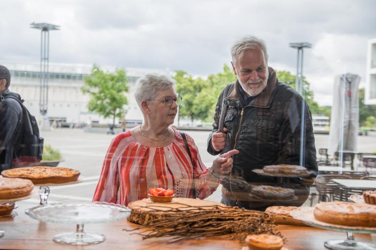 Man en senior vrouw kijken in etalage naar gebak