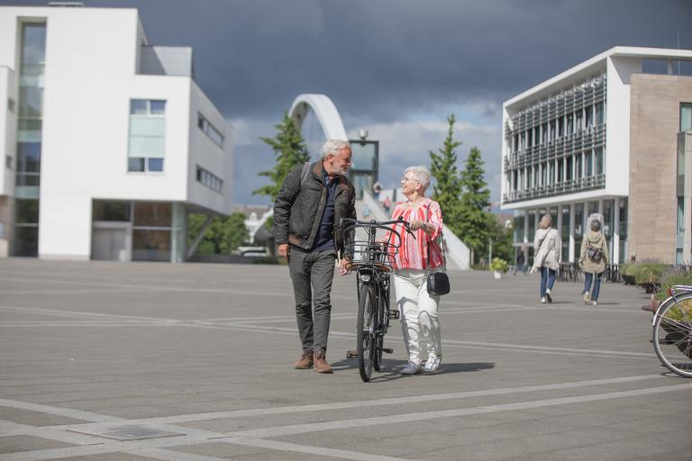 Man en senior vrouw met fiets op plein