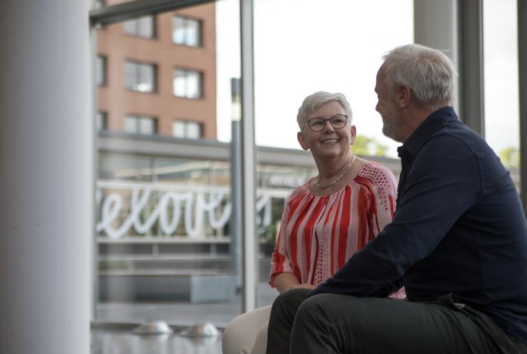 Senior vrouw met man op bankje binnen vriendelijk lachend