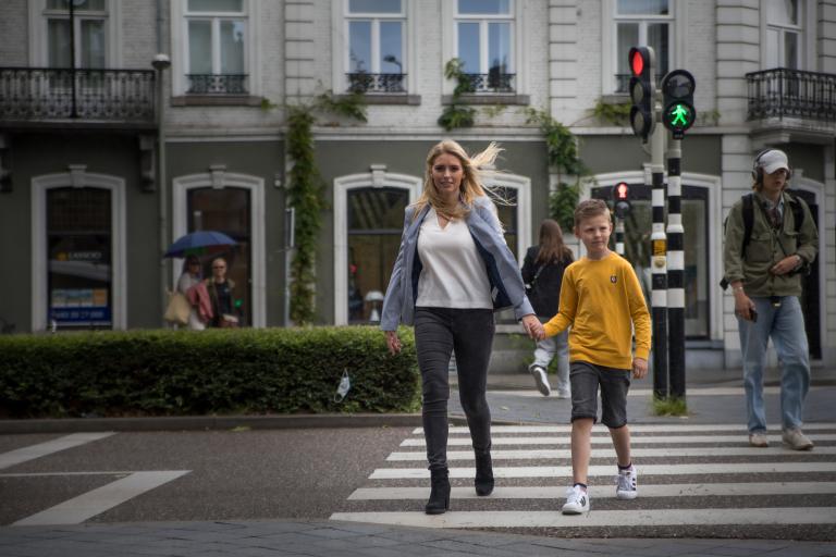 Blonde vrouw loopt met blond jongetje over zebrapad 