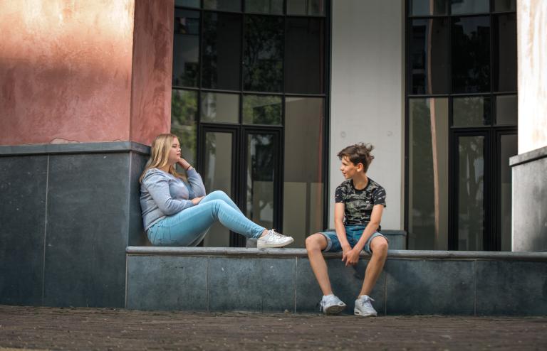 Jongetje en meisje zitten op een stoep