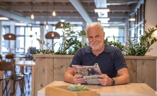 Man met baard aan tafel met tijdschrift in hand