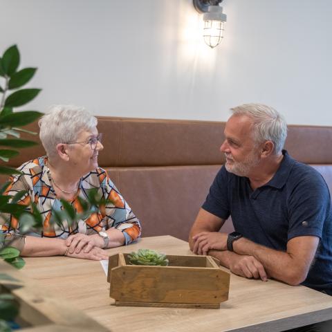 senior vrouw aan tafel in gesprek met man