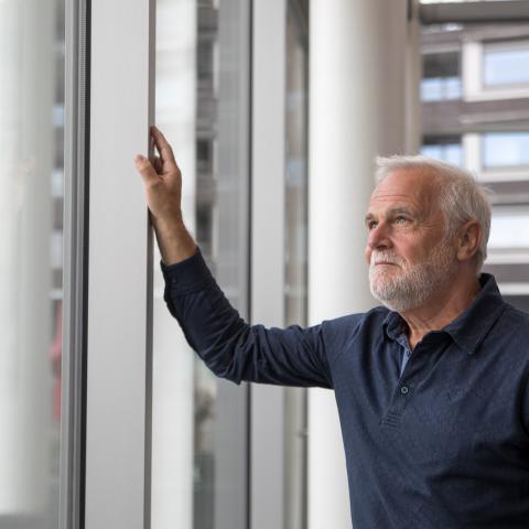Man met baard in gebouw tuurt naar buiten