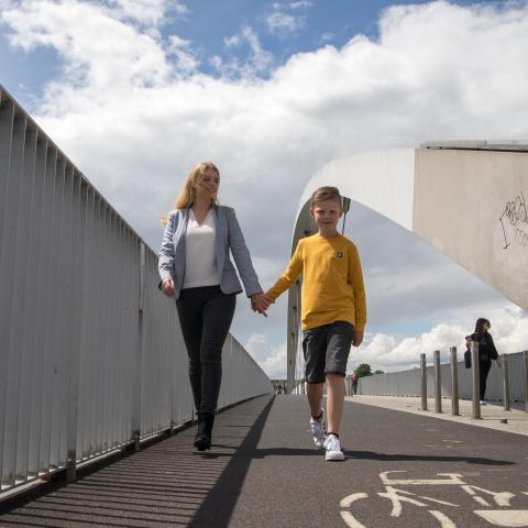 Blonde dame en blond jongetje lopen buiten op de brug